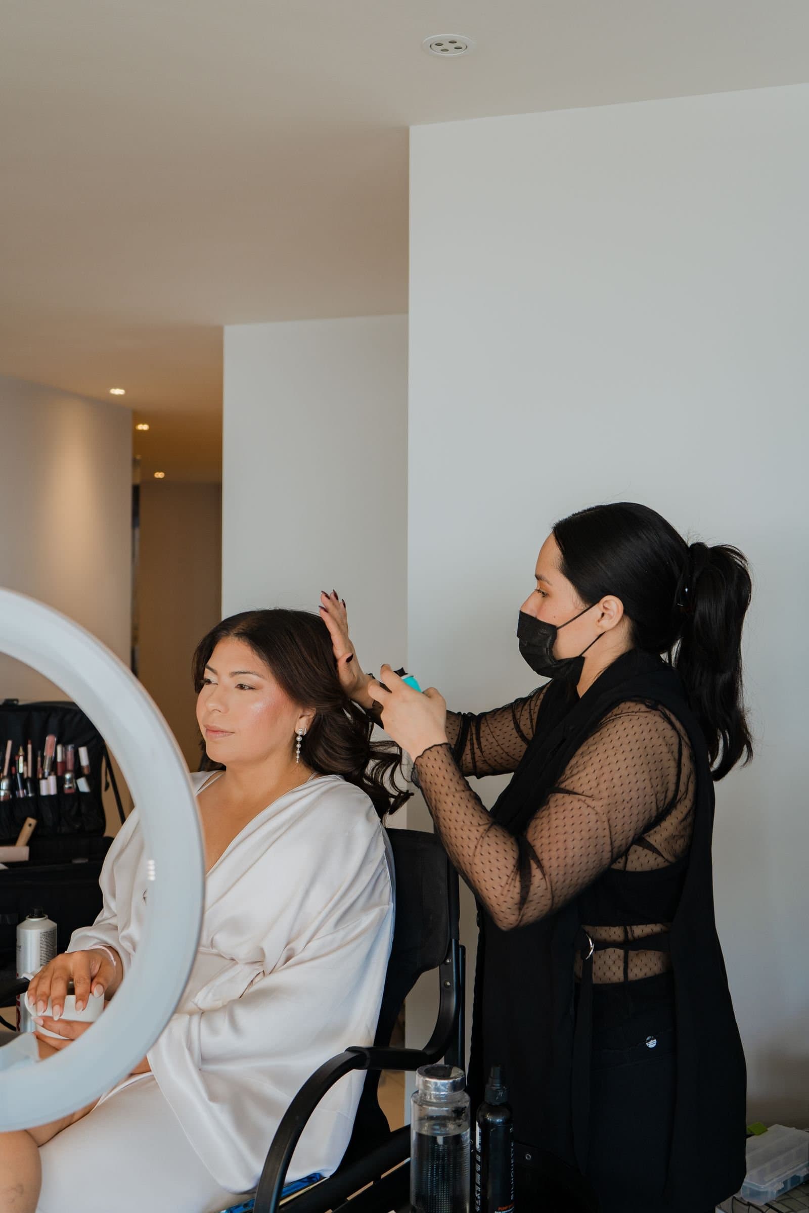 Novia en bata blanca durante su getting ready con una artista de Mich & Beauty