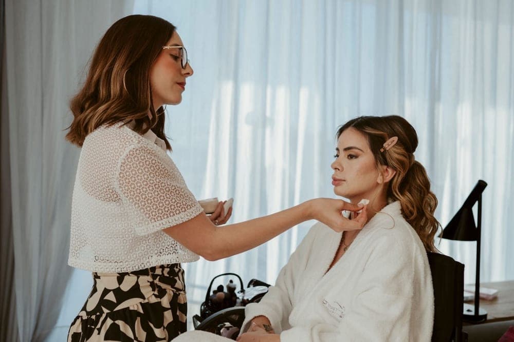 Artista de Mich & Beauty afinando el maquillaje con la luz de la ventana