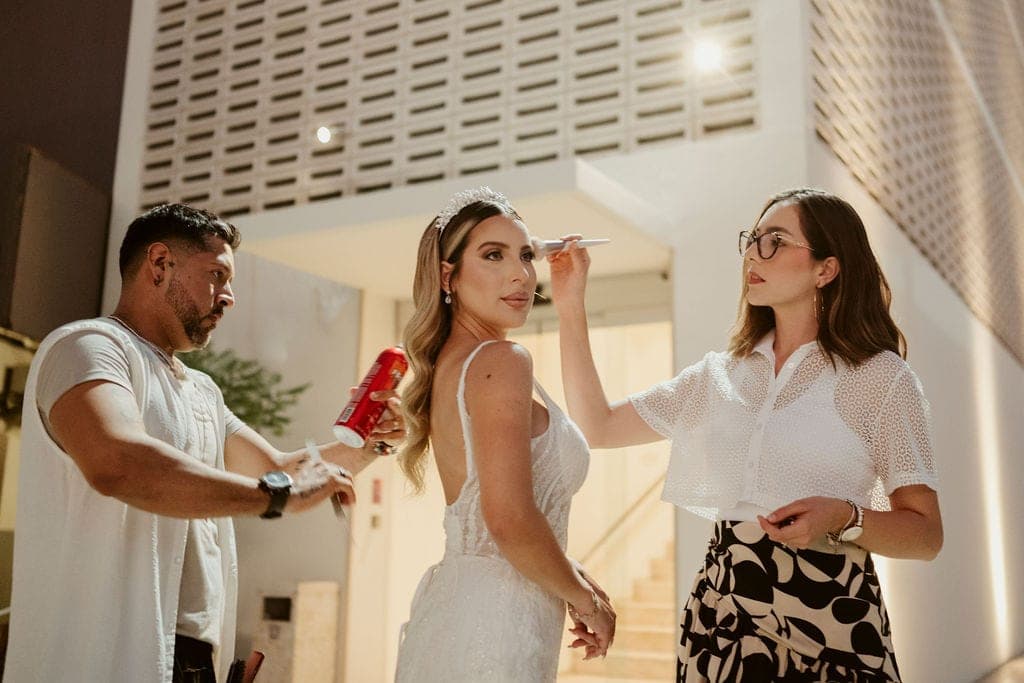 Dos artistas de Mich & Beauty retocando el peinado y el maquillaje de la novia antes de la ceremonia