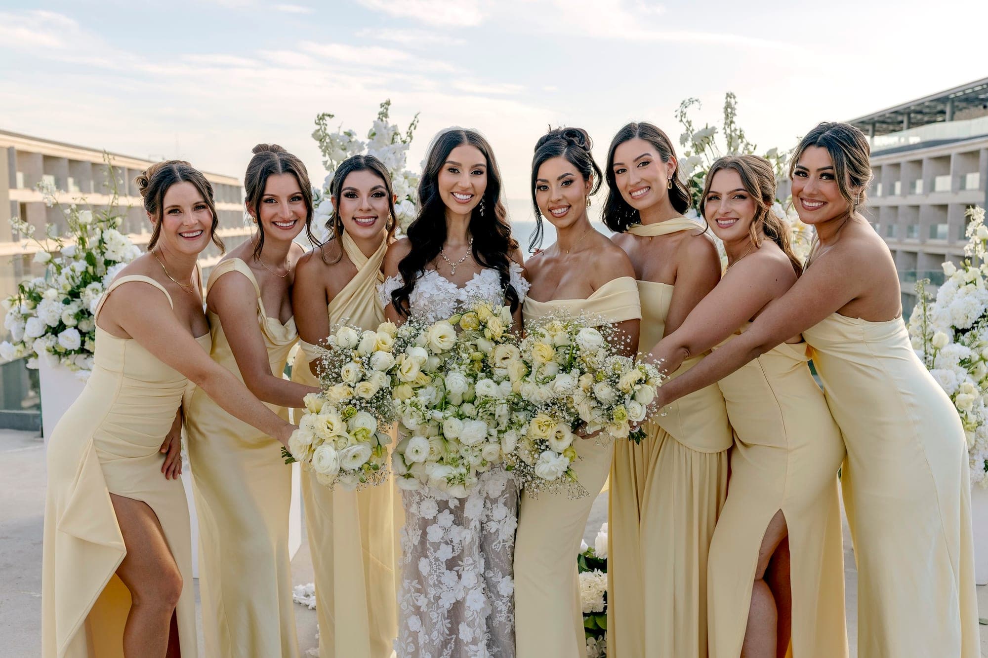 Novia rodeada de sus damas en vestidos amarillo claro, todas arregladas por el equipo
